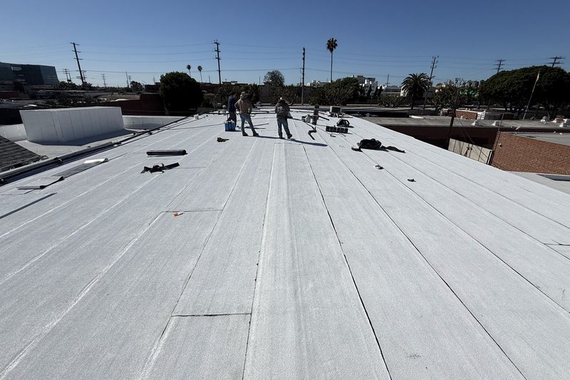 Roofing crew working across a broad white low-slope roof