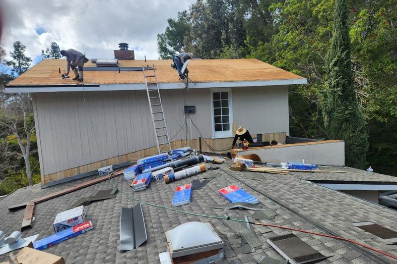 Residential roof during active replacement with exposed deck and staged materials