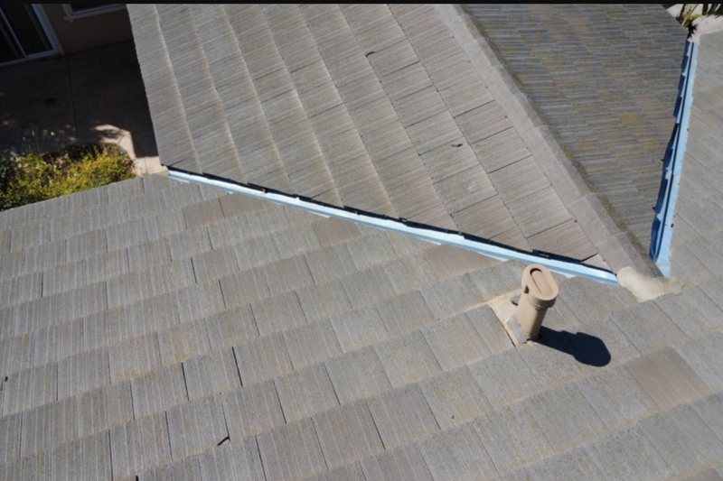 Weathered gray shingle roof planes meeting at a metal-lined valley