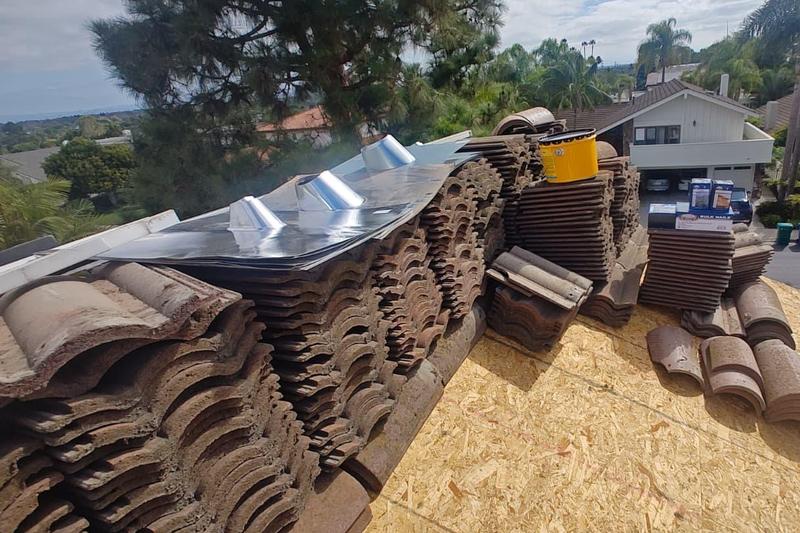 Stacks of roof tiles staged beside an exposed roof deck