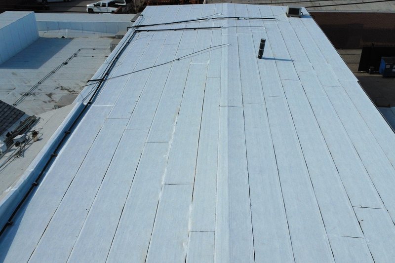 Aerial white low-slope roof with visible seams and penetrations